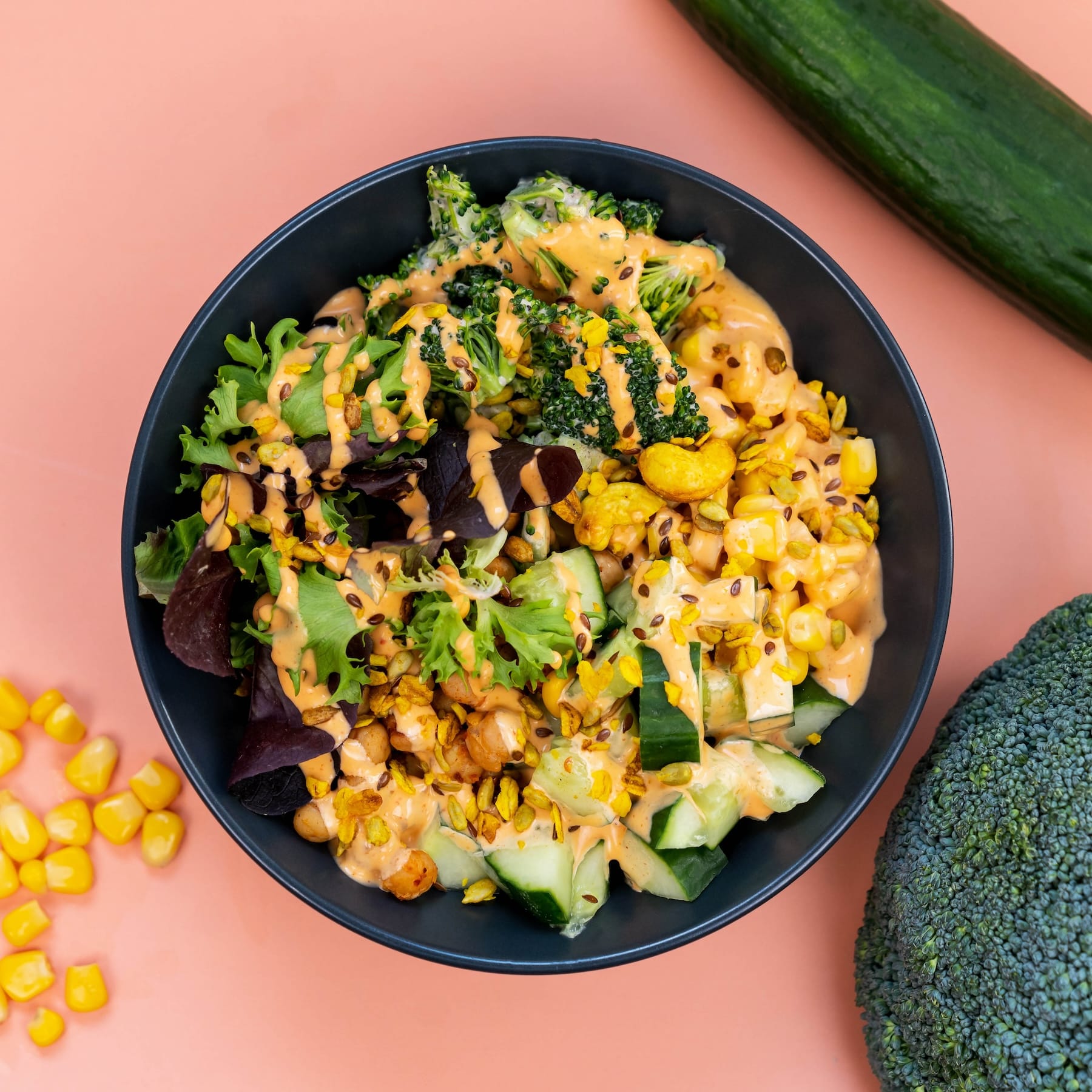 Wähle aus der Kategorie Bowls: ENERGIE BOWL mit Basis: Couscous. Mais, Gurke, Salat-Mix, Brokkoli-Salat, angebratene Kichererbsen und Kernmix mit Balsamico Dressing & veganer Chili Mayo.